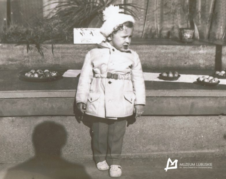Czarno-biale zdjęcie dziecka stojącego przy pisankach